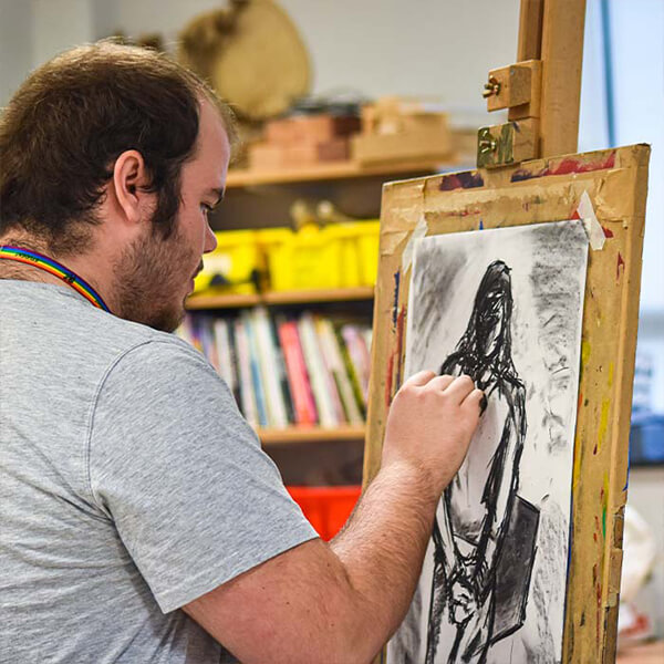 A man drawing a picture of a woman on an easel.