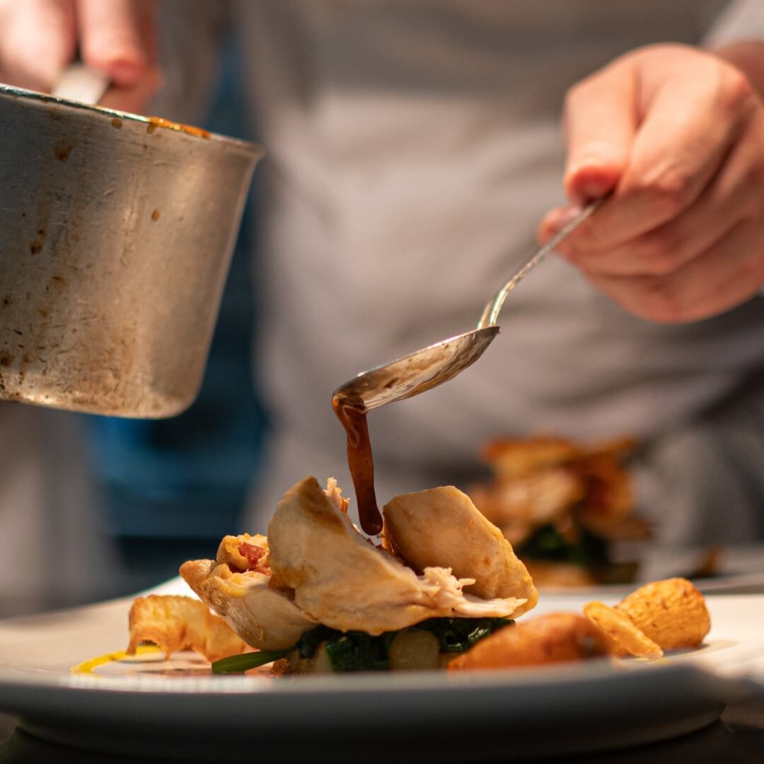 Gravy being drizzled onto a chicken dish.