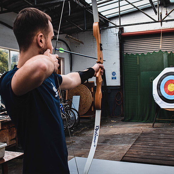 A Man holding a bow and arrow, shooting at a target.