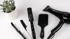 Close-up of hairdressing brushes and hairdryer laid on white surface